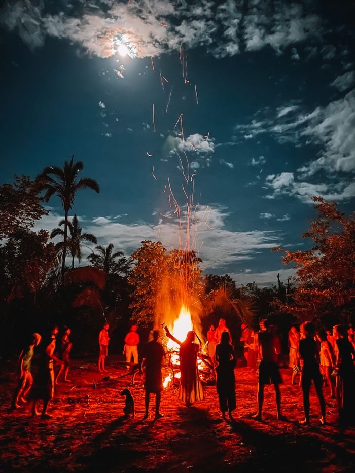 People silhouette during a ritual ceremony around a bonfire under a moonlit night in Brazil.